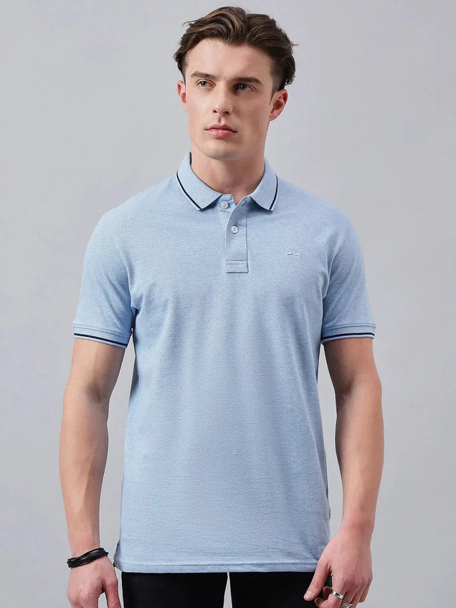 Man wears 98degreenorth Men's Sky Blue Solid Polo T-Shirt—Cotton Pique, standing against a plain gray background.