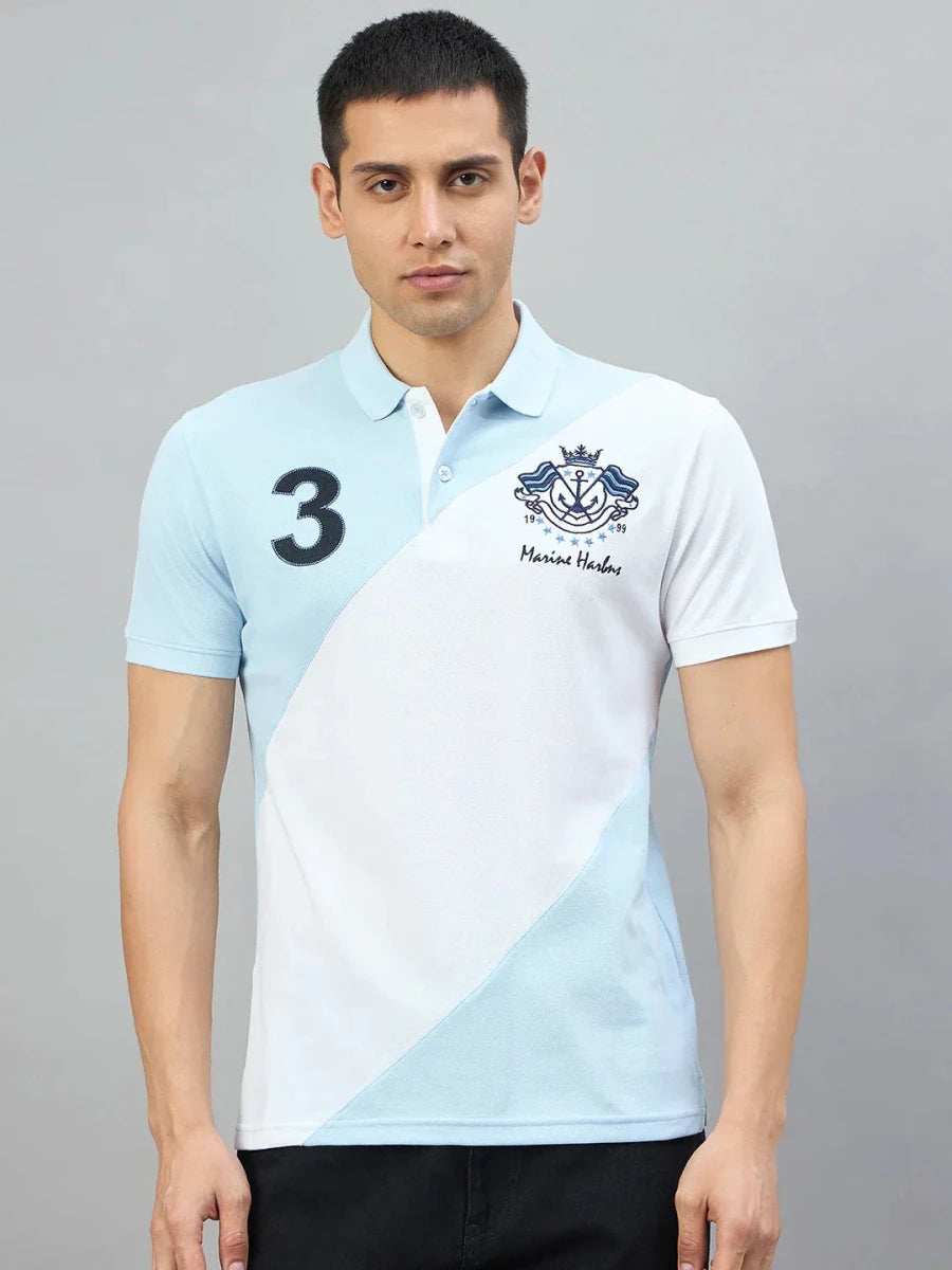 A man wears a 98degreenorth sky blue & white colour block polo with Marine Harbns embroidery against a gray background.
