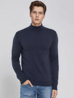 A man wears the 98degreenorth Men’s Teal Blue Merino Wool Turtle Neck Sweater against a plain light background.