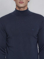Man wears 98degreenorth Men’s Teal Blue Merino Wool Turtle Neck Sweater, a fine-gauge pullover with chest logo.