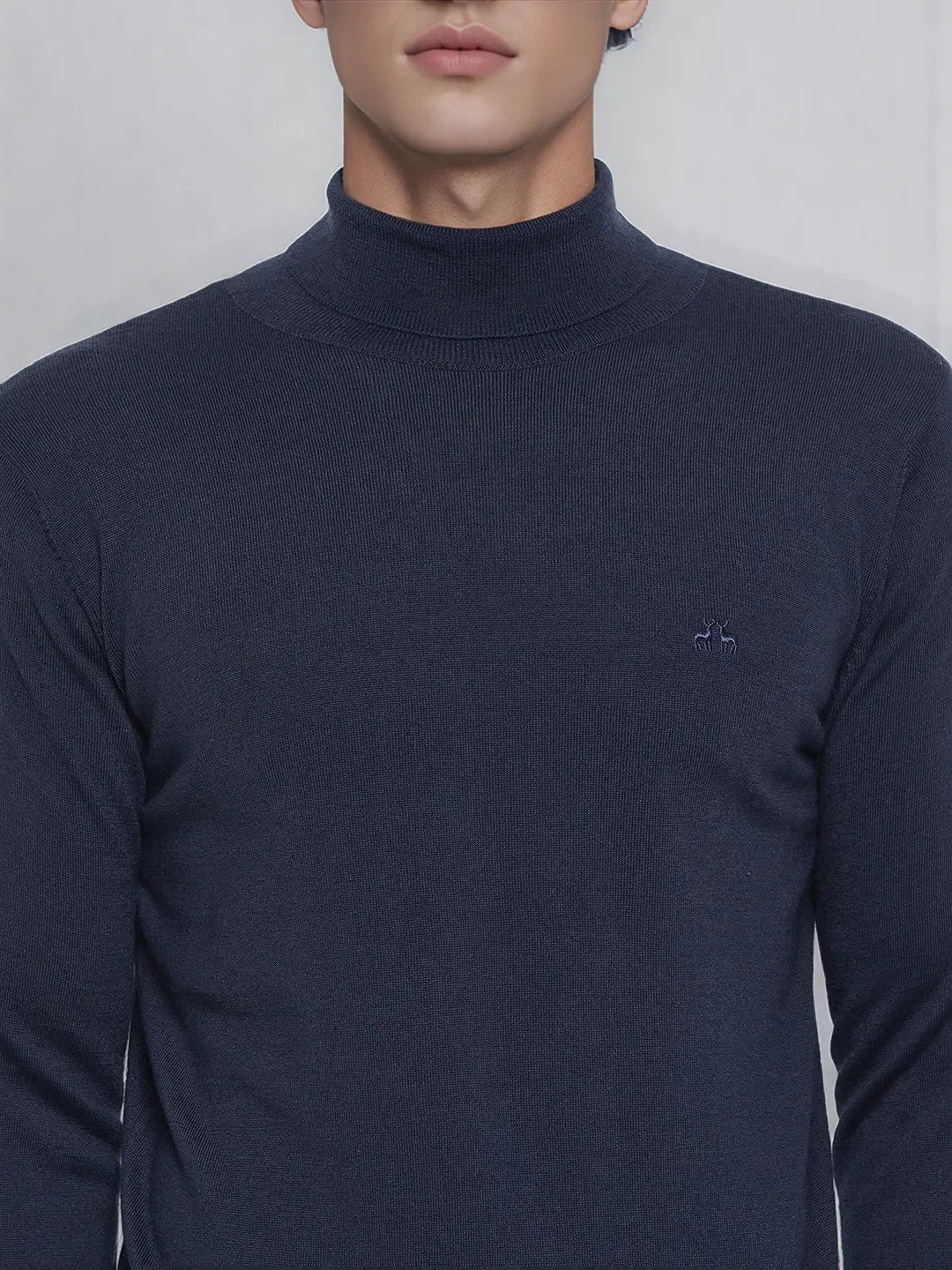 Man wears 98degreenorth Men’s Teal Blue Merino Wool Turtle Neck Sweater, a fine-gauge pullover with chest logo.