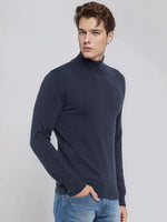 A man wears a 98degreenorth Men’s Teal Blue Merino Wool Turtle Neck Sweater against a plain light background.