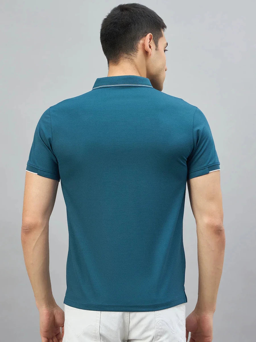 Man in a 98degreenorth men's teal polo with LA logo and white shorts, back to camera on plain background.