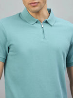 A man wears the 98degreenorth Men's Turquoise Quarter Zip Polo T-Shirt, standing against a gray background.