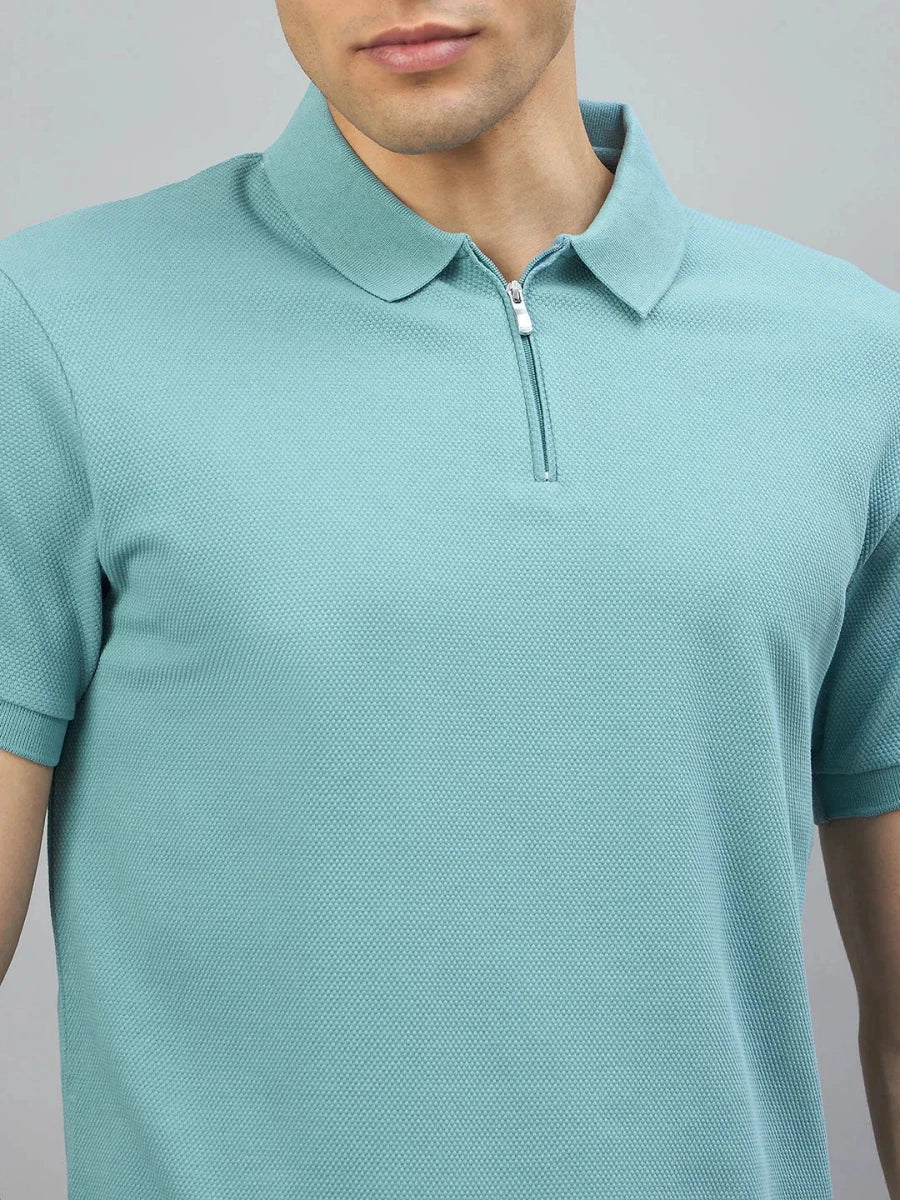 A man wears the 98degreenorth Men's Turquoise Quarter Zip Polo T-Shirt, standing against a gray background.
