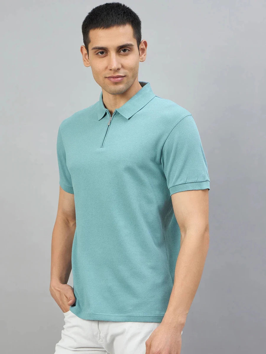 Man wears 98degreenorth Men's Turquoise Quarter Zip Polo T-Shirt, standing against a plain grey background.