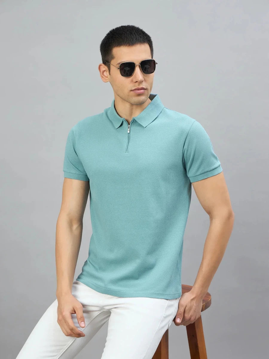 Man in sunglasses wears the 98degreenorth Men's Turquoise Quarter Zip Polo T-Shirt, sitting on a wooden stool.