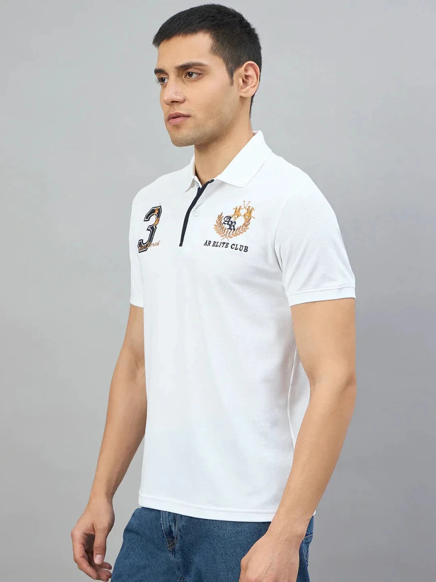 Man in Men's White AR Elite Club No.3 Polo T-Shirt by 98degreenorth stands against a grey background.