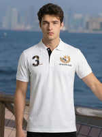 Man in a 98degreenorth Men's White AR Elite Club No.3 Polo T-Shirt, standing by a city waterfront.