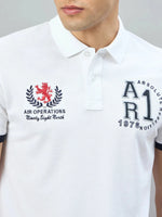 Man wears 98degreenorth Men's White Embroidered Polo T-Shirt with text and a red lion chest emblem.