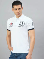 Man wearing a 98degreenorth Men's White Embroidered Polo T-Shirt, standing with one hand in his pocket, looking aside.