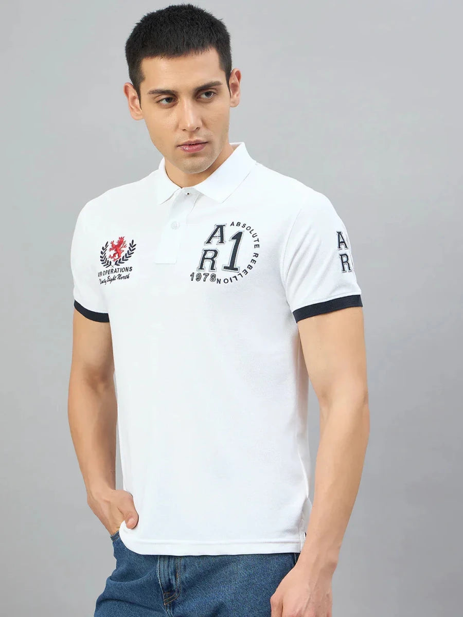 Man wearing a 98degreenorth Men's White Embroidered Polo T-Shirt, standing with one hand in his pocket, looking aside.