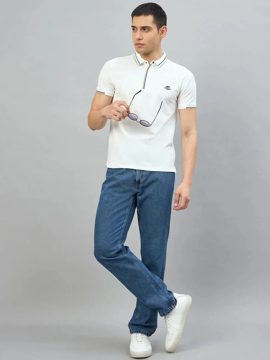 Man in 98degreenorth Men's White Polo T-Shirt — Handmade Series with contrast tipping, jeans, and sneakers on grey background.