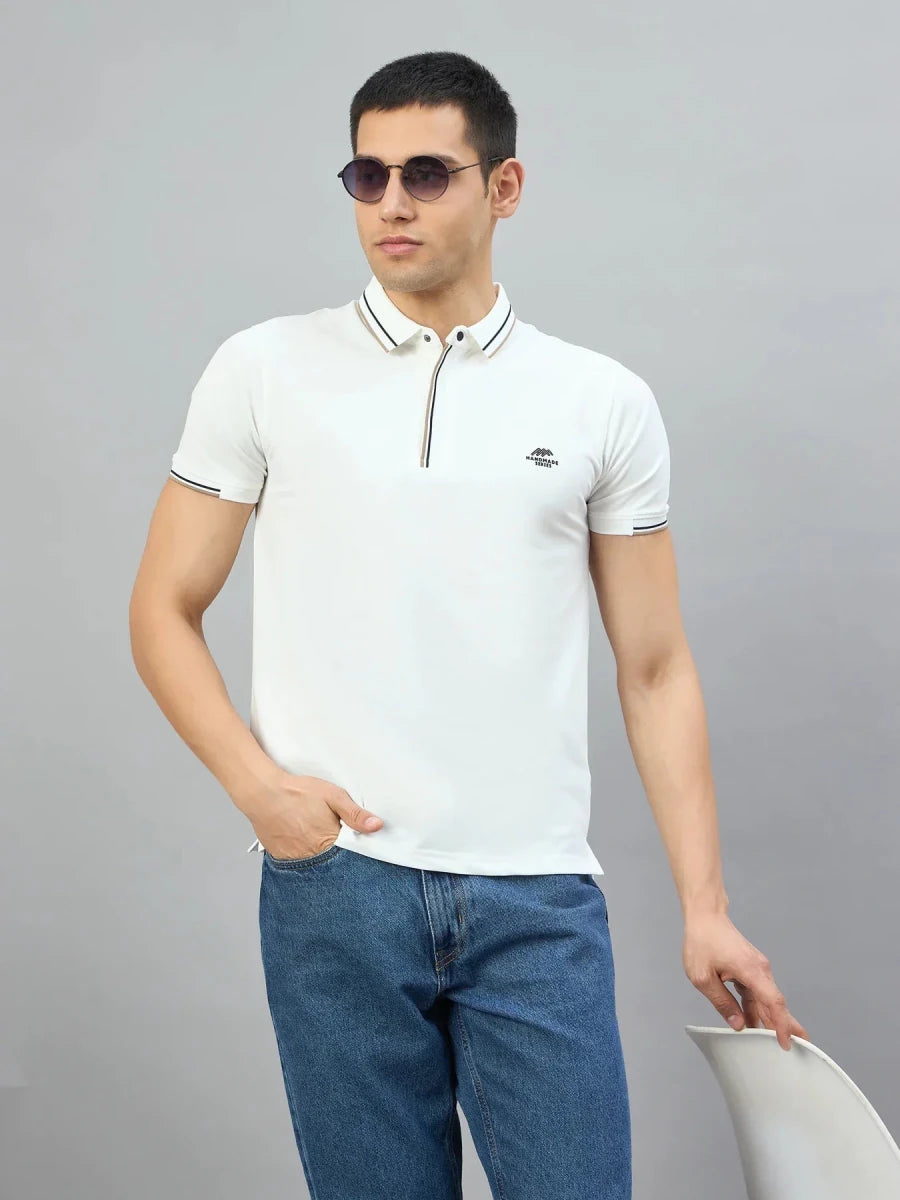 Man wears 98degreenorth Men's White Polo T-Shirt—Handmade Series, sunglasses, and jeans holding a white chair.