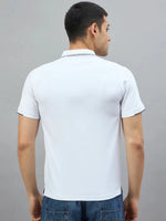 A man wears the 98degreenorth Men's White Polo with Navy Tipping and blue jeans, seen from the back on a gray background.