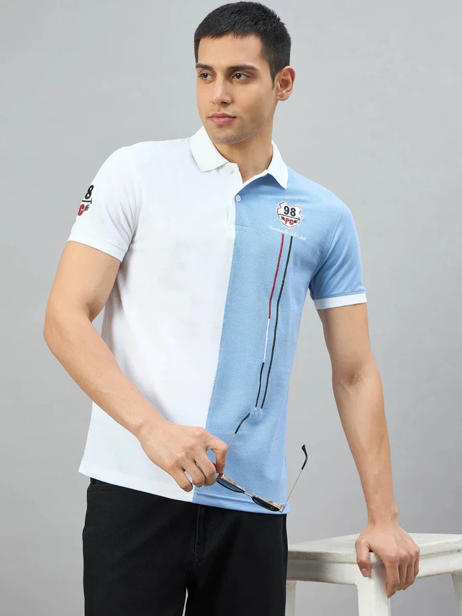 Man in 98degreenorth Men's White Sky Blue Colour Block Polo T-Shirt, holding sunglasses and leaning on a white chair.