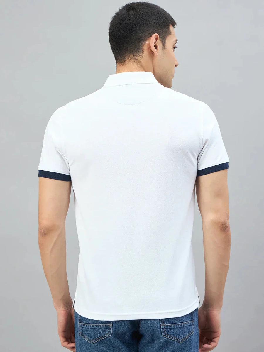 Man wears 98degreenorth Men's White Yachting Club Polo T-Shirt, paired with blue jeans, facing away against plain backdrop.