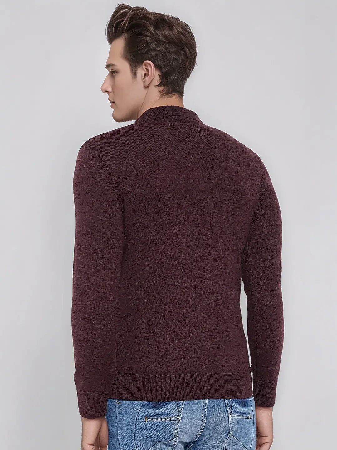 Man in a 98degreenorth Wine Merino Wool Polo Neck Sweater and blue jeans stands with his back to the camera.