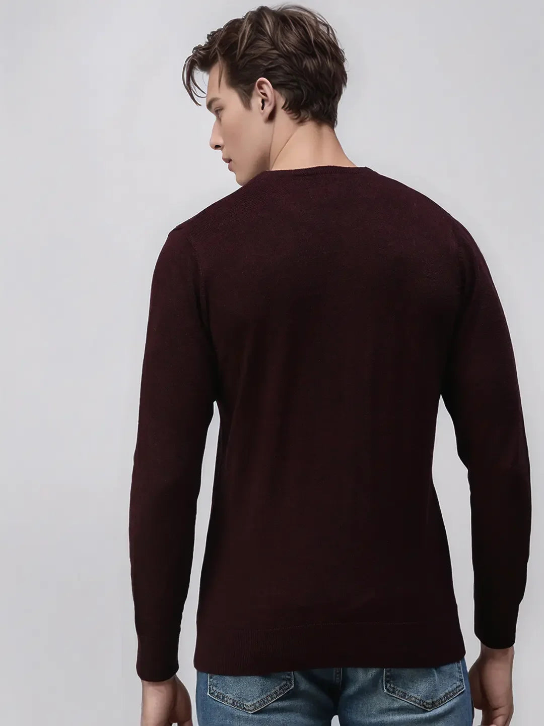 A man wears the 98degreenorth Men’s Wine Merino Wool Round Neck Sweater against a plain light background.