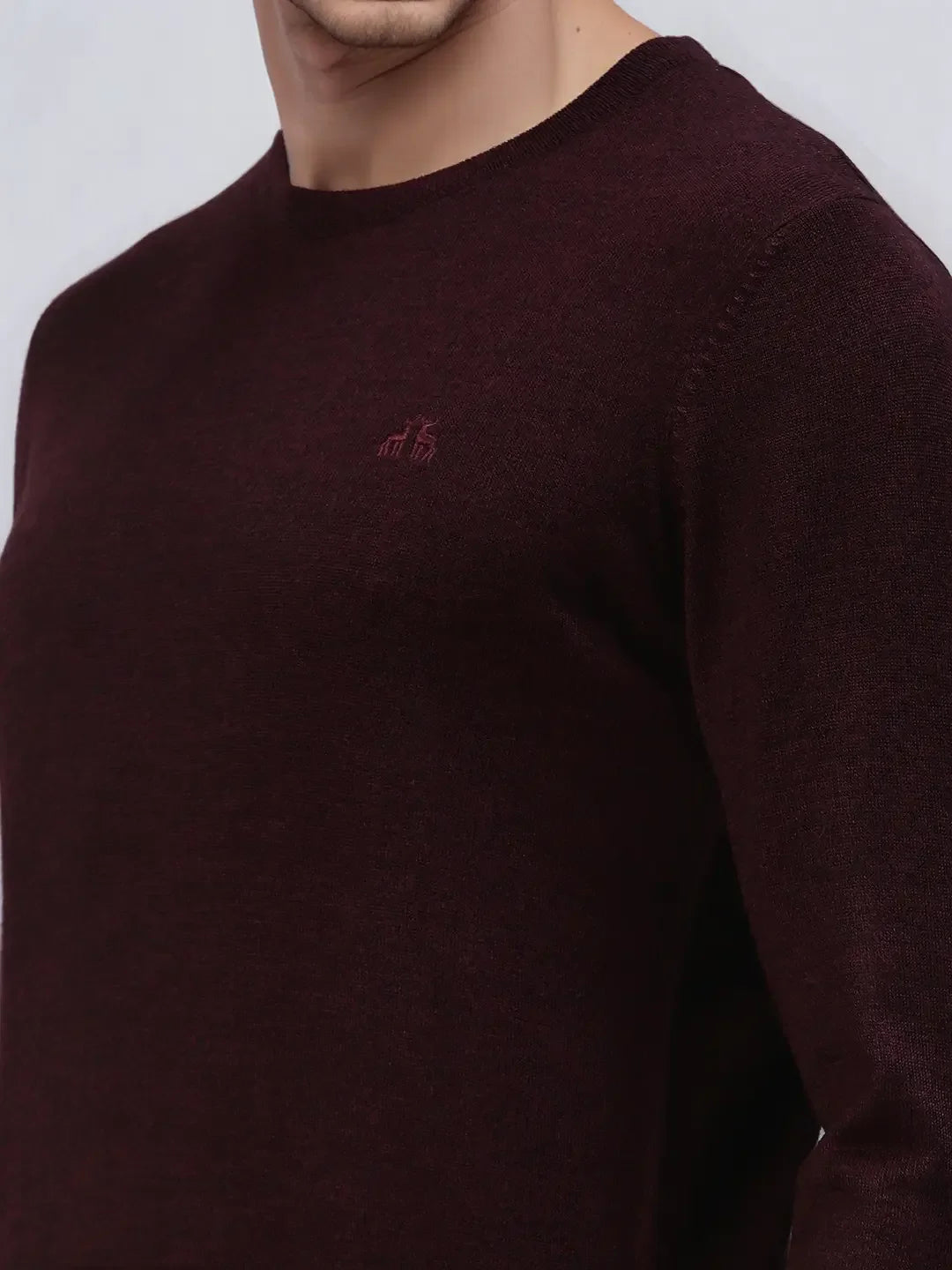 Man wears 98degreenorth Men’s Wine Merino Wool Round Neck Sweater, cropped at neck/waist, with small chest logo.