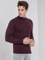 Man in 98degreenorth Men’s Wine Merino Wool Turtle Neck Sweater styled with light gray jeans against a plain backdrop.