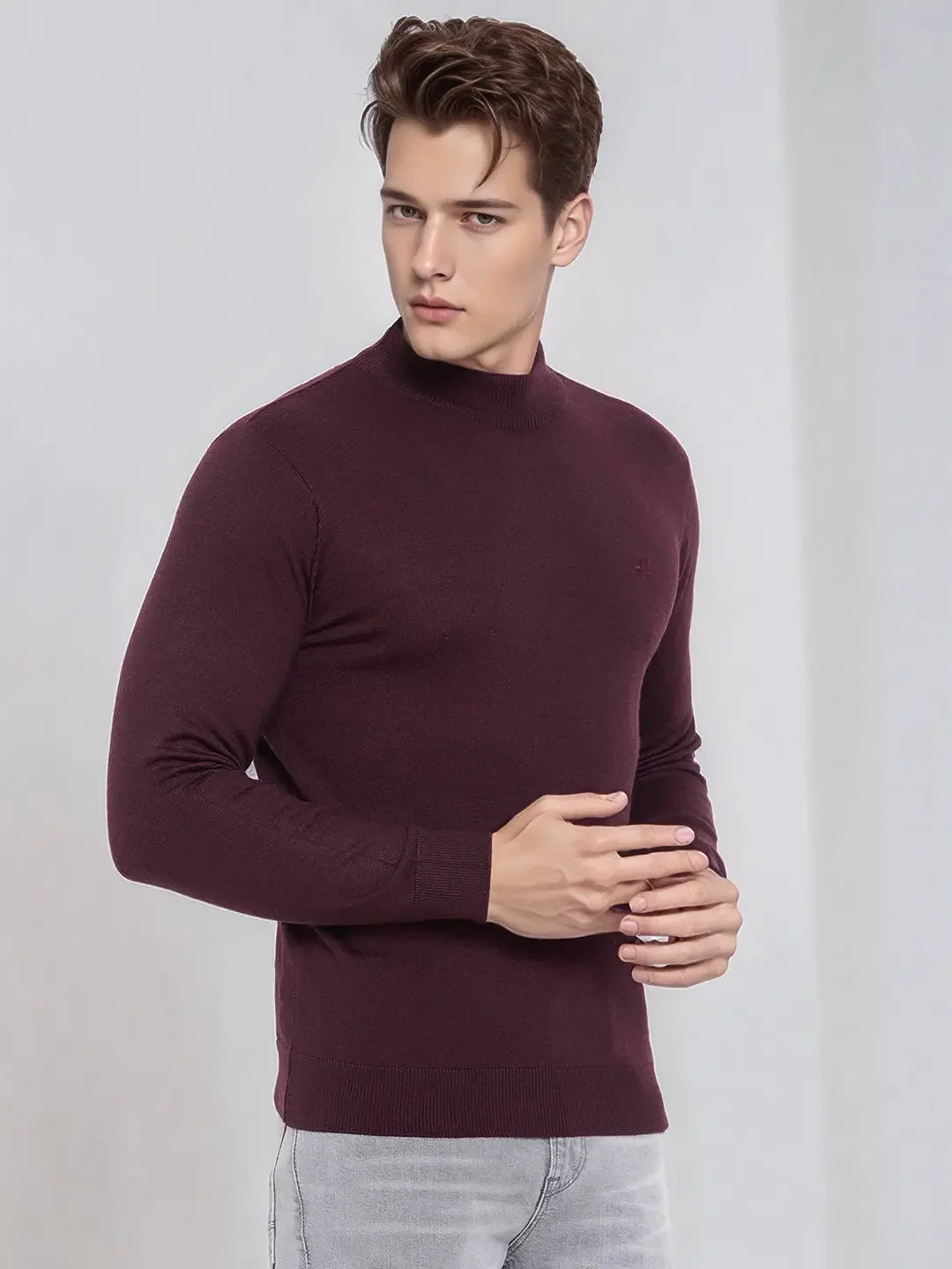 Man in 98degreenorth Men’s Wine Merino Wool Turtle Neck Sweater styled with light gray jeans against a plain backdrop.