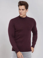 A man wears a 98degreenorth Wine Merino Wool Turtle Neck Sweater with light grey jeans against a plain background.
