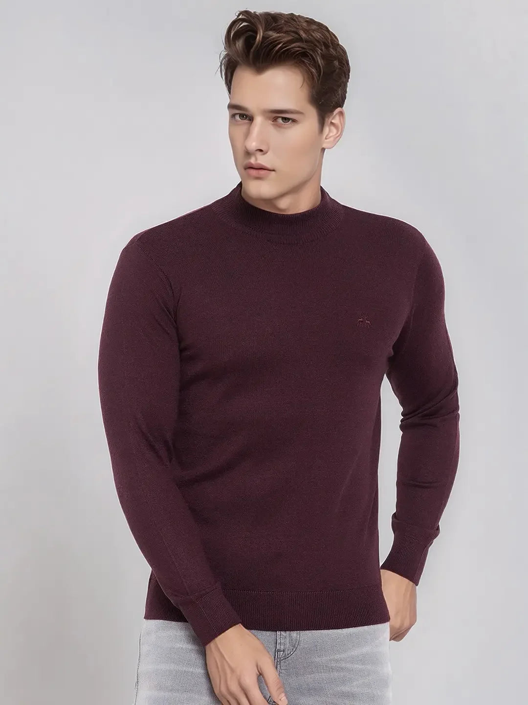 A man wears a 98degreenorth Wine Merino Wool Turtle Neck Sweater with light grey jeans against a plain background.