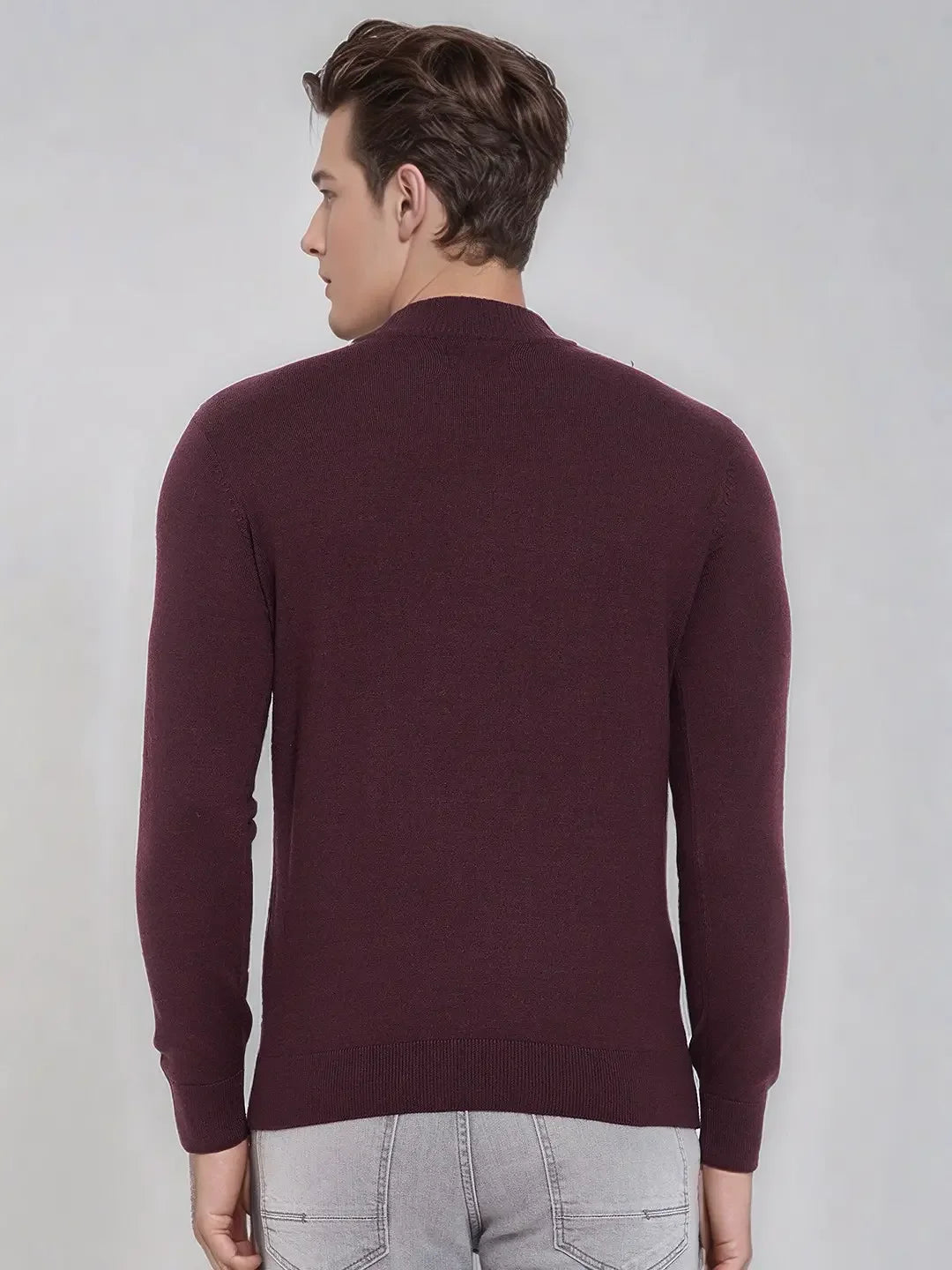 A man in a 98degreenorth wine Merino wool turtle neck sweater and light gray jeans stands facing away against a plain background.