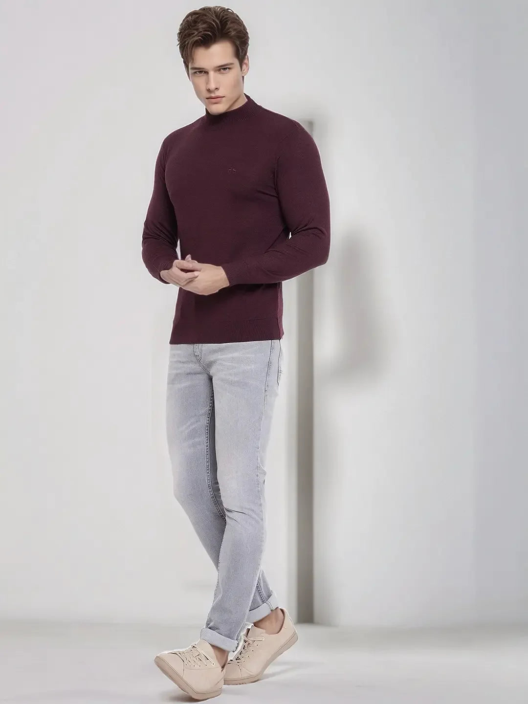 Man in 98degreenorth Men’s Wine Merino Wool Turtle Neck Sweater poses stylishly in light gray jeans against a plain background.
