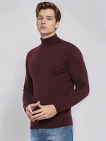 Man in a 98degreenorth Men’s Wine Merino Wool Turtle Neck Sweater, blue jeans, poses against a plain light background.