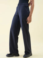 Person wears 98degreenorth Navy Wide Leg Pintuck Trackpants with black shoes against a plain light background.
