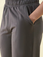 A person in 98degreenorth Olive Wide Leg Pintuck Trackpants, one hand in pocket, shown waist to mid-thigh.