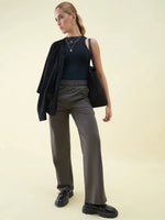 Woman in a black tank top and 98degreenorth Olive Wide Leg Pintuck Trackpants stands against a plain light background.