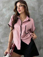 Woman wears 98degreenorth Pink Whipstitch Trim Cotton Shirt, holding a magazine against a gray background.