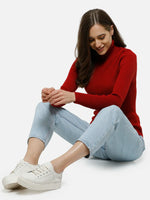 Woman in 98degreenorth Red Ribbed Stretchable Turtleneck Sweater and light blue jeans smiles while sitting on the floor.