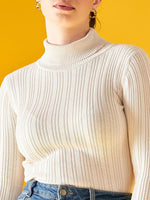 A woman wears a 98degreenorth Ribbed Offwhite Turtle Neck Pullover with blue jeans, standing against a bright yellow background. Only her upper body is visible, and her hair is pulled back.
