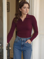 Woman with brown hair wears the 98degreenorth Rosewood Ribbed Collared Sweater, standing in a doorway and looking aside.
