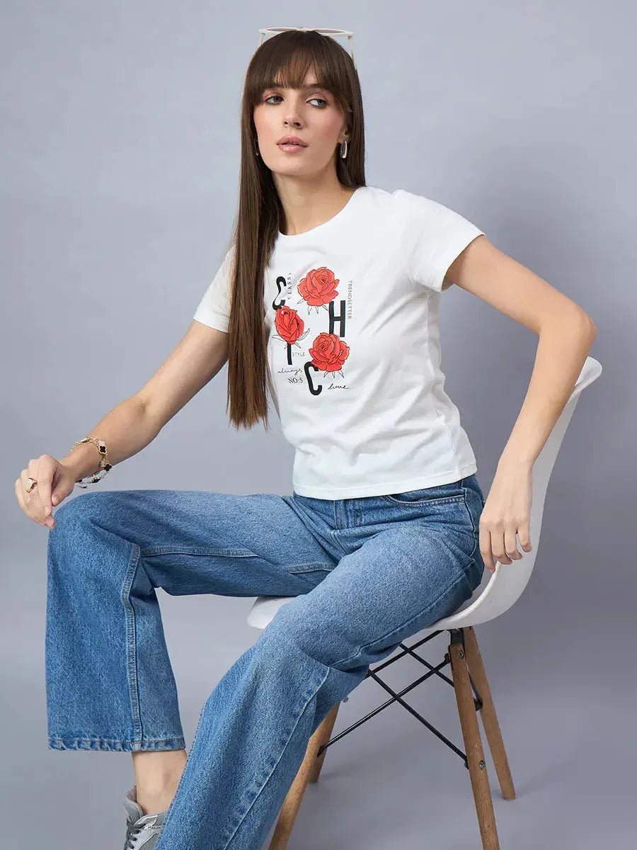 Woman in a 98degreenorth round-neck cotton tee with bold typography print and blue jeans sits on a white chair.