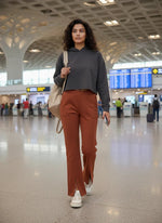 Woman in 98degreenorth Rust Melange Fleece Bootcut Sweatpants walks through airport, phone in hand, backpack on shoulder.