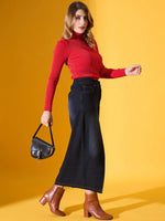 Woman in a 98degreenorth Scarlet Red Ribbed Turtleneck Sweater, wide-leg jeans, brown boots, holding a black purse.