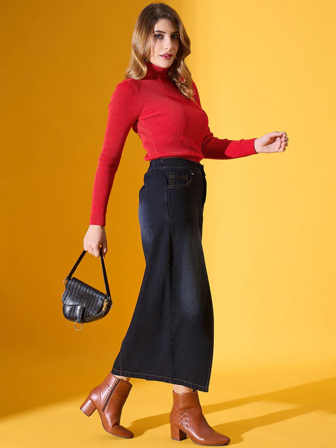 Woman in a 98degreenorth Scarlet Red Ribbed Turtleneck Sweater, wide-leg jeans, brown boots, holding a black purse.