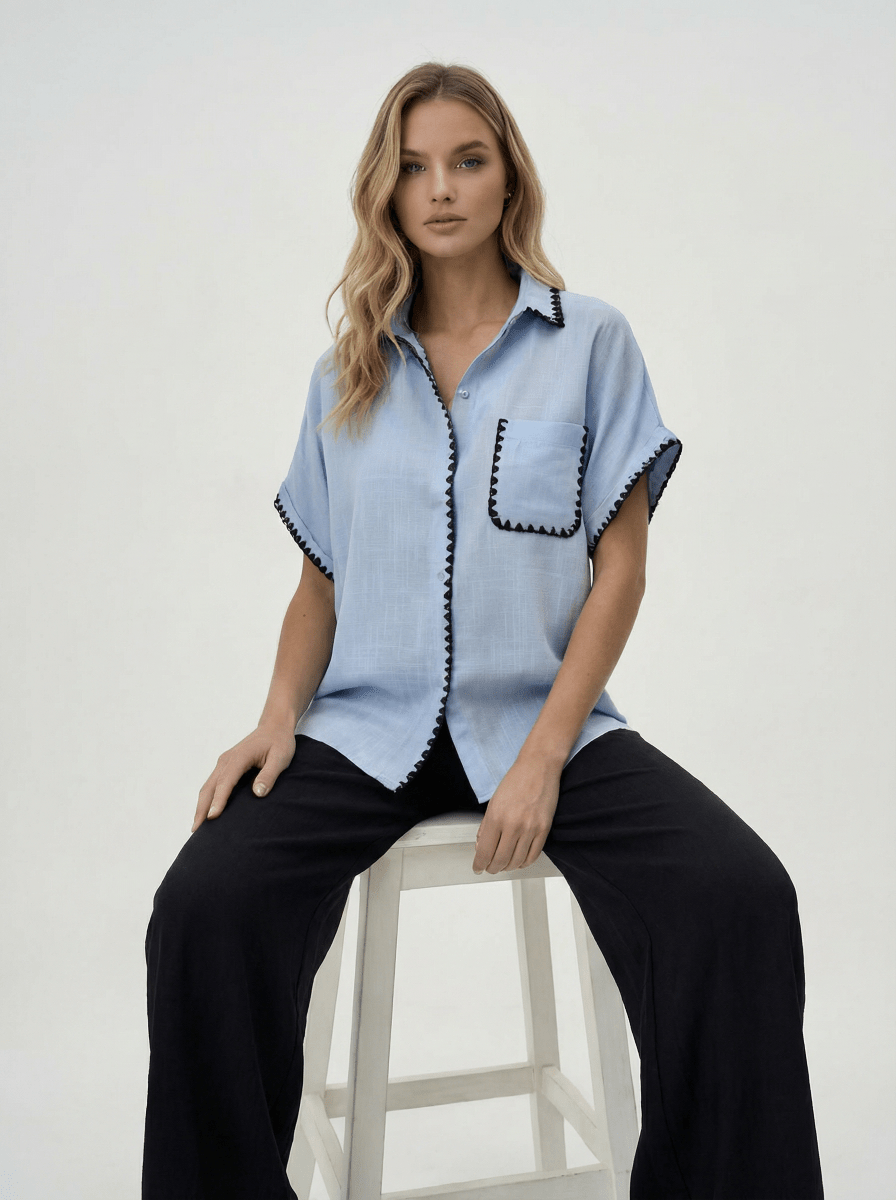 Woman wears 98degreenorth Sky Blue Whipstitch Trim Cotton Shirt and black pants, Luxe Summer collection.