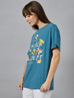 Woman wears 98degreenorth Stylish Typography Printed T-shirt – round neck, drop shoulder – with white pants.
