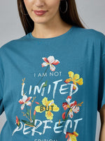 Woman in a 98degreenorth Stylish Typography Printed T-shirt—denim color, round neck, drop shoulder, floral design.