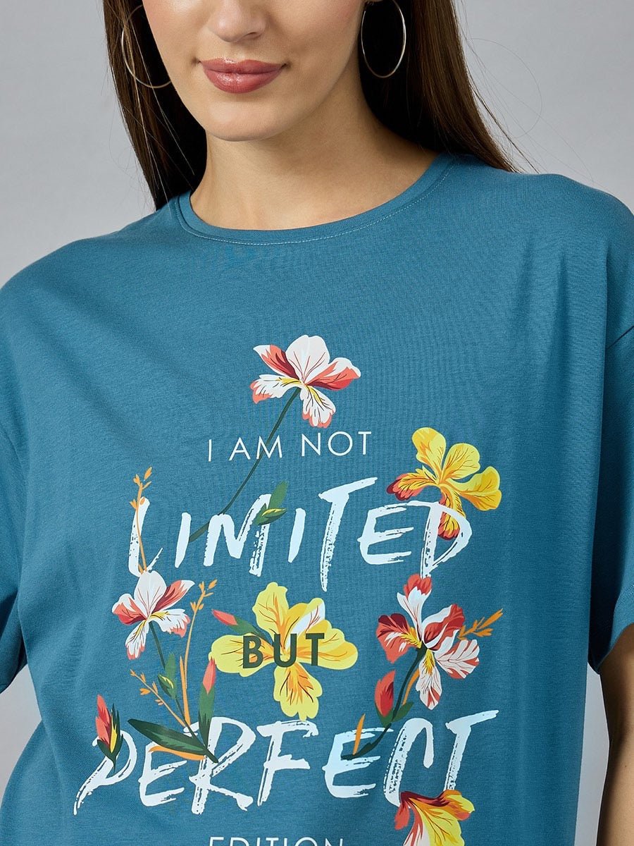 Woman in a 98degreenorth Stylish Typography Printed T-shirt—denim color, round neck, drop shoulder, floral design.