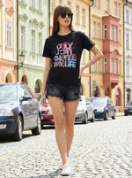 A woman in sunglasses wears the 98degreenorth Trendy Typography Cotton Tee for Girls on a cobblestone street.