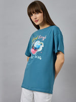 Woman in a 98degreenorth Trendy Typography Graphic T-shirt – cotton, round neck, drop shoulder – with white pants.