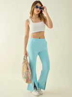 Woman models 98degreenorth Turquoise Blue Fleece Bootcut Sweatpants with sunglasses and a patterned bag.