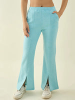 Woman wearing 98degreenorth Turquoise Blue Fleece Bootcut Sweatpants with front slits and white sneakers, hands in pockets.